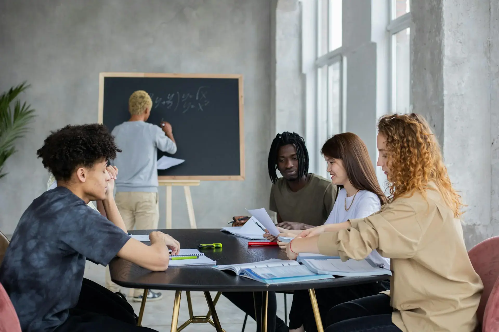 Diverse students learning mathematics with teacher at chalkboard