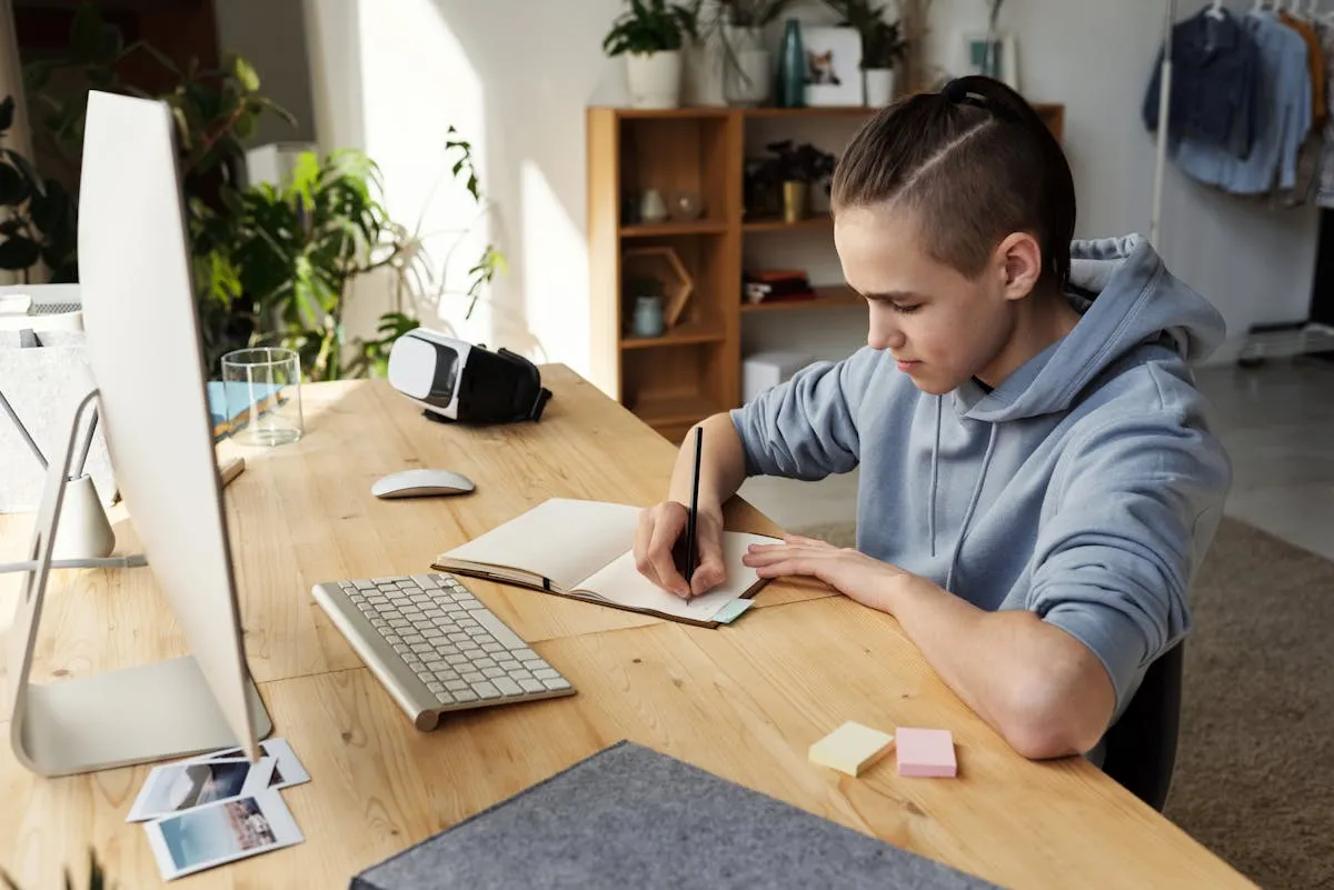A-Level student studying at home with notes and laptop