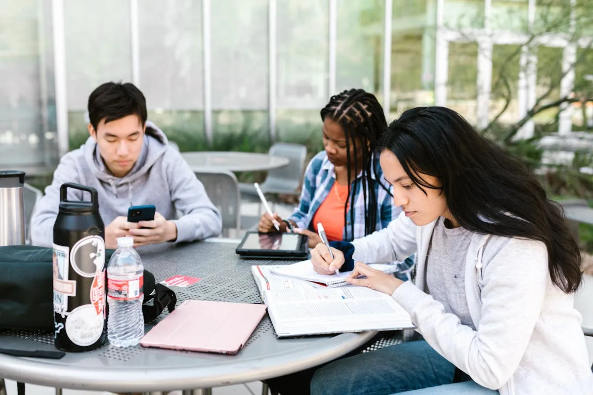 Diverse group of IGCSE students studying together with tablets and notebooks