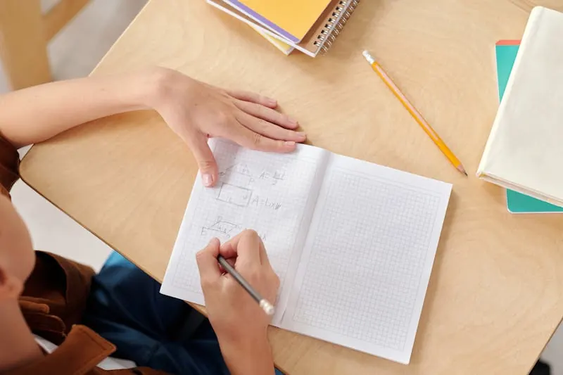A student working through problems in a notebook
