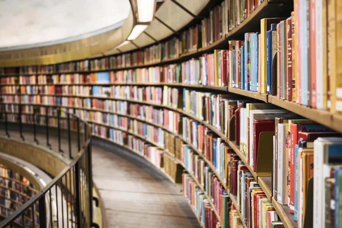 A-Level student studying in a library with academic textbooks and laptop
